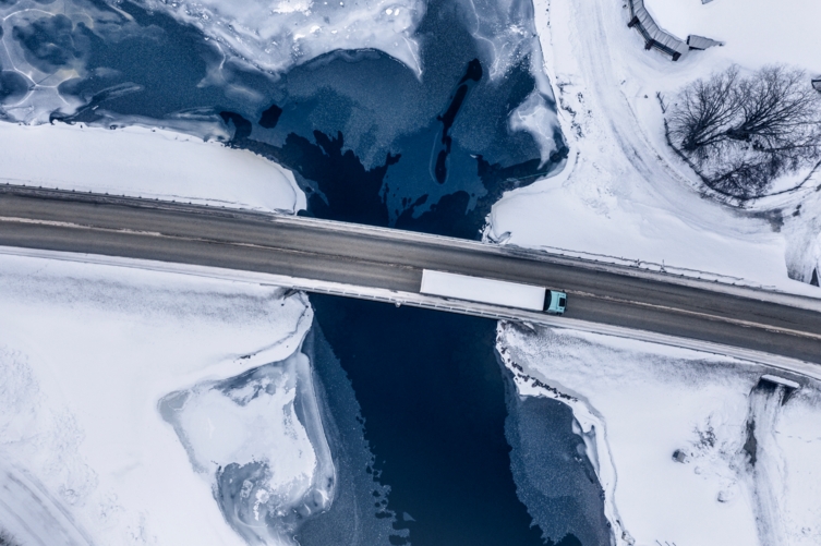 Bluekens-truck-en-bus-Volvo-Electric-rijdend-over-brug-in-sneeuw-landschap-van-boven